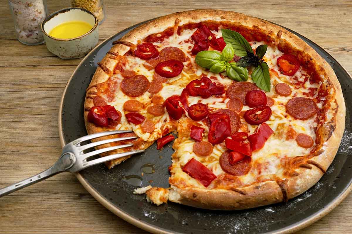 食べかけのピザとフォークがプレートに盛られている